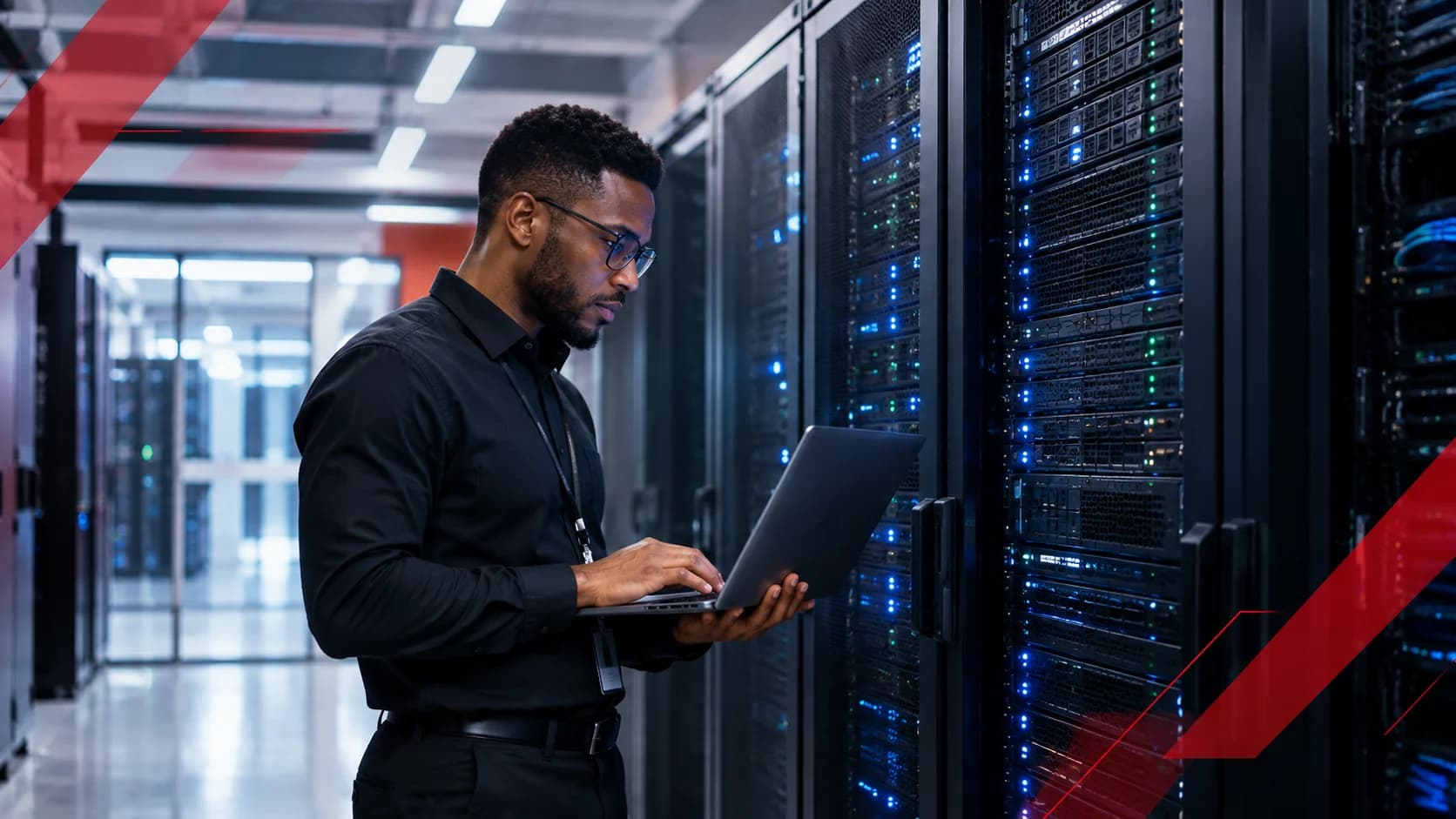 An engineer working on a laptop beside rows of enterprise server racks